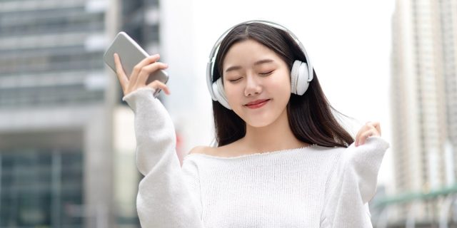 Asian girl wearing headphones and listening to streaming music